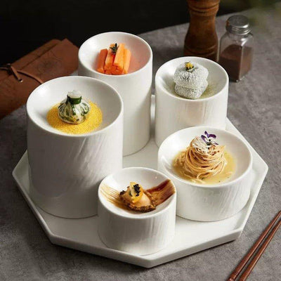 A set of white ceramic cylindrical serving dishes arranged on a tray, containing various food items.