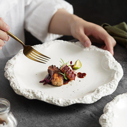 White ceramic dinner plate with an irregular, textured rock-like rim